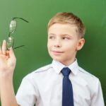 A confident Caucasian student admiring his spectacles lenses