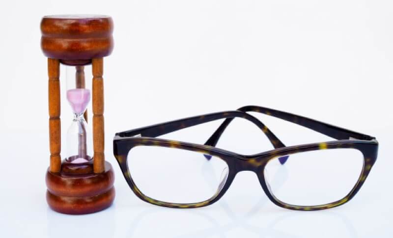 Spectacles beside an hourglass indicating time is running out