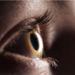 Zoomed-in brown eye looking up towards a weak light source